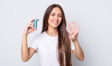 Genç, güzel bir bayan gülümsüyor ve arkadaş canlısı görünüyor, dört numarayı gösteriyor. astım konsepti