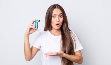 Genç ve güzel bir kadın şaşırmış ve şok olmuş görünüyor. Çenesi düşmüş ve elinde bir nesne tutuyor. astım konsepti