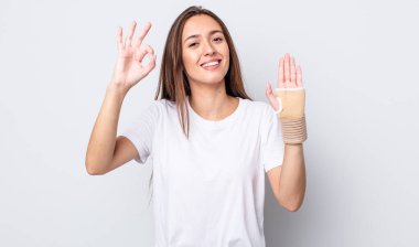 Genç ve güzel bir kadın kendini mutlu hissediyor. Onayını iyi bir hareketle gösteriyor. el bandajı konsepti