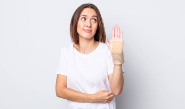 Genç, güzel bir kadın omuz silkiyor, kafası karışık ve kararsız. el bandajı konsepti