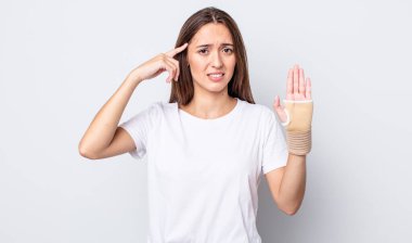 Genç ve güzel bir kadın kafası karışık ve şaşkın hissediyor, deli olduğunu gösteriyor. el bandajı konsepti