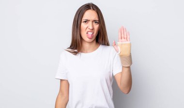 Genç ve güzel bir kadın iğreniyor, sinirleniyor ve dilini çıkarıyor. el bandajı konsepti