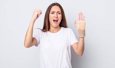 Genç ve güzel bir kadın sinirli bir ifadeyle agresif bir şekilde bağırıyor. el bandajı konsepti