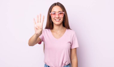 Genç, güzel bir bayan gülümsüyor ve arkadaş canlısı görünüyor, dört numarayı gösteriyor. pembe güneş gözlüğü konsepti