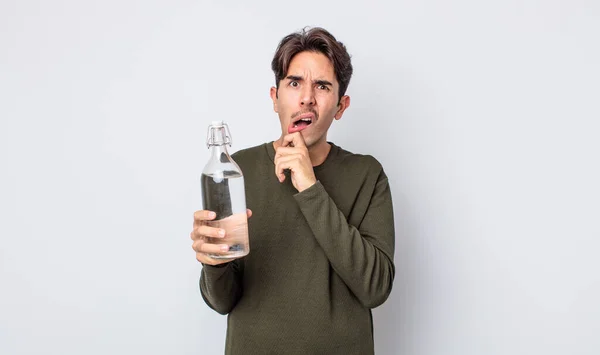 口と目の広い若いヒスパニック系の男が開いて顎に手を ウォーターボトルのコンセプト — ストック写真