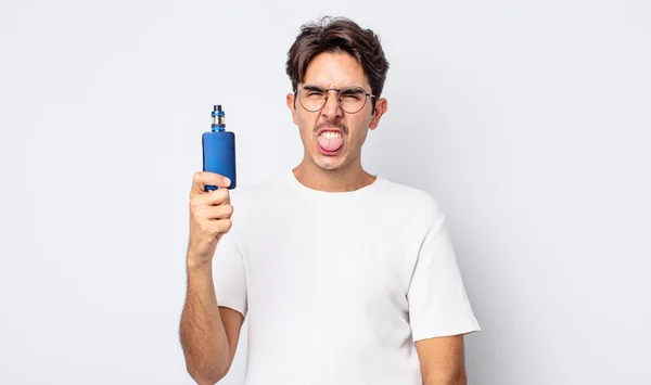 若いヒスパニック系の男はうんざりし いらいらし 舌を出す感じ 煙蒸発器の概念 — ストック写真