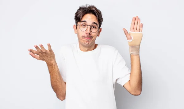 Young Hispanic Man Feeling Puzzled Confused Doubting Hand Bandage Concept — Stock Photo, Image