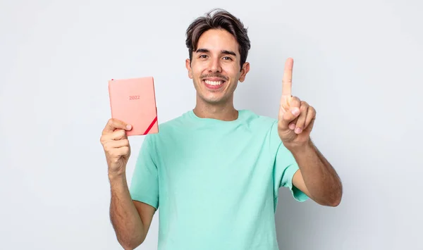 Joven Hispano Sonriendo Luciendo Amigable Mostrando Número Uno Concepto Planificador — Foto de Stock