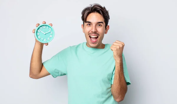 若いヒスパニック系の男はショックを感じます 笑いと成功を祝う 目覚まし時計のコンセプト — ストック写真