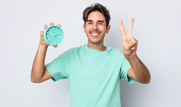 若いヒスパニック系の男は笑顔と友好的に見える 2番目を示す 目覚まし時計のコンセプト — ストック写真