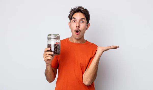 若いヒスパニック系の男が驚いてショックを受け 顎が物を持って落下した コーヒー豆のコンセプト — ストック写真