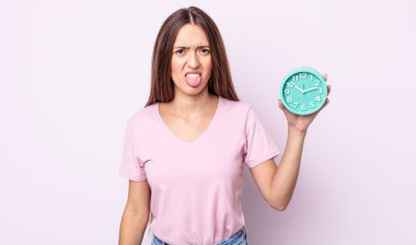 Genç ve güzel bir kadın iğreniyor, sinirleniyor ve dilini çıkarıyor. Alarm saati kavramı