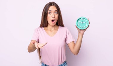 Genç ve güzel bir kadın şok olmuş ve şaşırmış hissediyor. Alarm saati kavramı