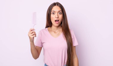 Genç ve güzel bir kadın çok şaşırmış ya da şaşkın görünüyor. saç tarağı konsepti