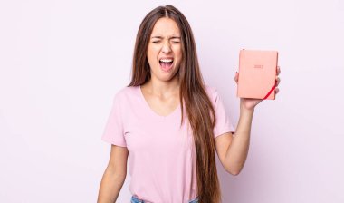 Genç ve güzel bir kadın agresif bir şekilde bağırıyor, çok kızgın görünüyor. 2022 planlayıcı kavramı