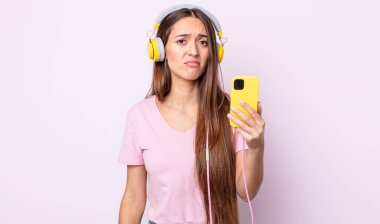 Genç, güzel bir kadın üzgün ve mızmızlanıyor. Mutsuz bir bakışı var ve ağlıyor. Kulaklık ve akıllı telefon.