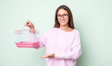 Genç, güzel bir kadın neşeyle gülümsüyor, mutlu hissediyor ve bir konsept gösteriyor. evcil hayvan kafesi