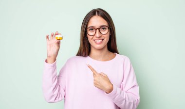 Genç, güzel bir kadın neşeyle gülümsüyor, mutlu hissediyor ve bir tarafı işaret ediyor. kontak lensler konsepti