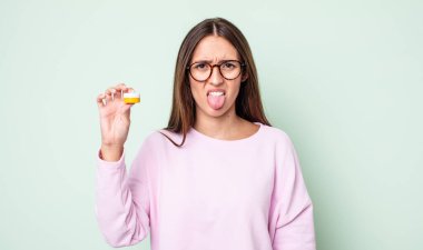 Genç ve güzel bir kadın iğreniyor, sinirleniyor ve dilini çıkarıyor. kontak lensler konsepti