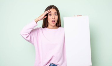 Genç ve güzel bir kadın mutlu, şaşkın ve şaşırmış görünüyor. boş tuval kavramı