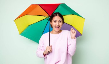 Genç ve güzel bir kadın şokta, gülüyor ve başarıyı kutluyor. şemsiye kavramı