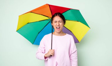 Genç ve güzel bir kadın agresif bir şekilde bağırıyor, çok kızgın görünüyor. şemsiye kavramı