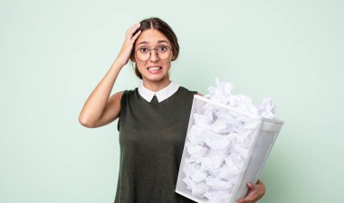 Genç ve güzel bir kadın gergin, endişeli ya da korkmuş hissediyor. Elleri başının üstünde. kağıt toplar çöp konsepti