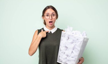 Şok olmuş ve ağzı açık, kendini gösteren genç ve güzel bir kadın. kağıt toplar çöp konsepti