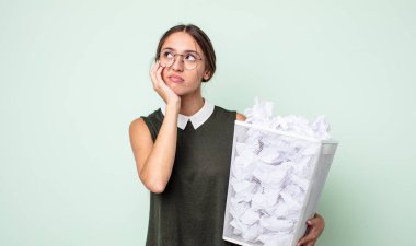 Genç ve güzel bir kadın sıkıcı, bıkkın ve uykulu hissediyor. kağıt toplar çöp konsepti