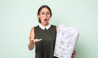 Genç ve güzel bir kadın şok olmuş ve şaşırmış hissediyor. kağıt toplar çöp konsepti