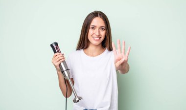 Genç, güzel bir bayan gülümsüyor ve arkadaş canlısı görünüyor, dört numarayı gösteriyor. el karıştırıcı konsepti