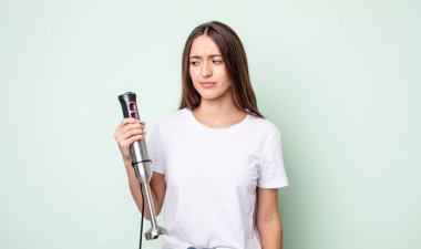 Genç, güzel bir kadın üzgün, üzgün ya da kızgın hissediyor ve yan tarafa bakıyor. el karıştırıcı konsepti