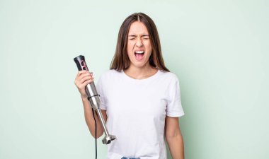 Genç ve güzel bir kadın agresif bir şekilde bağırıyor, çok kızgın görünüyor. el karıştırıcı konsepti