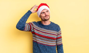 Kafası karışmış, kafası karışmış, kaşınan genç, yakışıklı bir adam. Noel konsepti