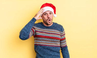 Genç yakışıklı adam mutlu, şaşkın ve şaşırmış görünüyor. Noel konsepti