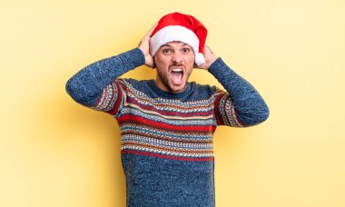 Genç ve yakışıklı bir adam stresli, endişeli ya da korkmuş hissediyor. Elleri başının üstünde. Noel konsepti