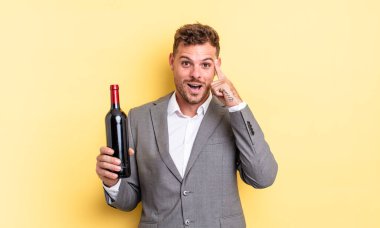Genç yakışıklı adam şaşırmış görünüyor, yeni bir düşünce, fikir ya da konsept fark ediyor. Şarap şişesi konsepti
