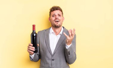 Genç yakışıklı adam umutsuz, sinirli ve stresli görünüyor. Şarap şişesi konsepti