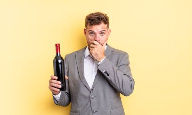 Genç ve yakışıklı bir adam elleri ile ağzını kapatıyor ve şok geçiriyor. Şarap şişesi konsepti