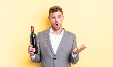 Genç ve yakışıklı bir adam şok olmuş ve şaşırmış hissediyor. Şarap şişesi konsepti