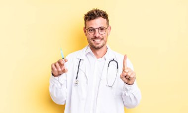 Genç yakışıklı adam gülümsüyor ve arkadaş canlısı görünüyor, bir numarayı gösteriyor. doktor şırınga konsepti