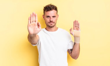 Genç ve yakışıklı adam ciddi görünüyor. Avuç içi gösteriyor. Durdurma hareketi yapıyor. el bandajı konsepti