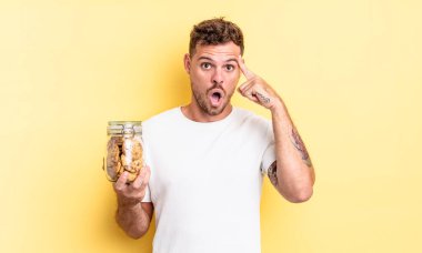 Genç yakışıklı adam şaşırmış görünüyor, yeni bir düşünce, fikir ya da konsept kurabiye şişesi konseptini fark ediyor.