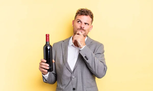 Jovem Homem Bonito Pensando Sentindo Duvidoso Confuso Garrafa Vinho Conceito — Fotografia de Stock