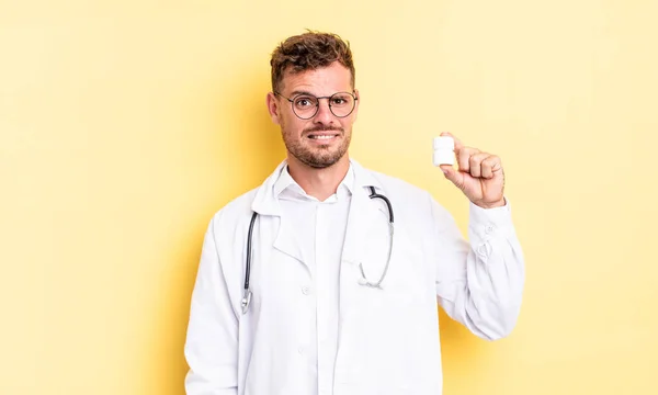 Jeune Homme Beau Sentant Perplexe Confus Médecin Pilules Bouteille Concept — Photo