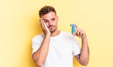 Genç yakışıklı bir adam bıkkın, hayal kırıklığına uğramış ve yorucu bir geceden sonra uykulu hissediyor. astım konsepti