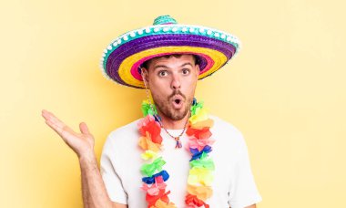 Genç, yakışıklı adam şaşırmış ve şok olmuş görünüyor. Çenesi düşmüş, elinde bir nesne var. Meksika partisi konsepti