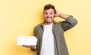 Genç ve yakışıklı bir adam stresli, endişeli ya da korkmuş hissediyor. Elleri başının üstünde. beyaz kutu kavramı