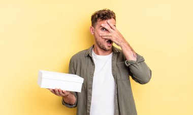 Genç, yakışıklı adam şok olmuş, korkmuş ya da korkmuş görünüyor. beyaz kutu kavramı