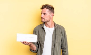 Profilde genç yakışıklı bir adam hayal kuruyor, hayal kuruyor ya da hayal kuruyor. beyaz kutu kavramı